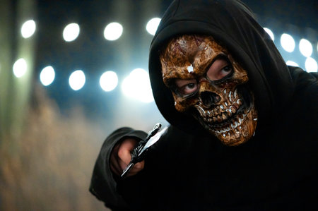 A man with a dagger and a halloween monster face on bokeh lights backgroundの写真素材