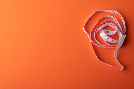 Measuring tape on orange background, fitness and diet conceptの写真素材