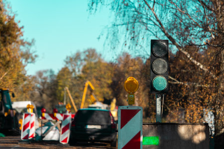 Green light at the traffic light and road repair equipment in  blurred background