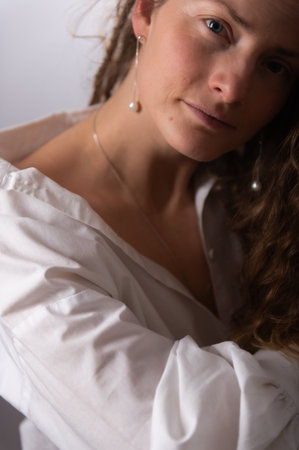 Beautiful woman with bare shoulder. Attractive woman with long curly hair. Naturally beautiful face without makeup. Natural female beauty.の写真素材