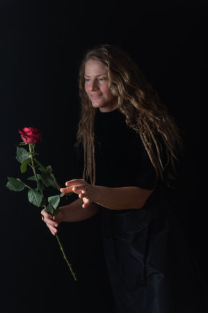 Pretty woman with red rose. Beauty studio portrait. Beautiful model with red rose flower, isolated on black studio background. Charming young natural girl without makeup.の写真素材