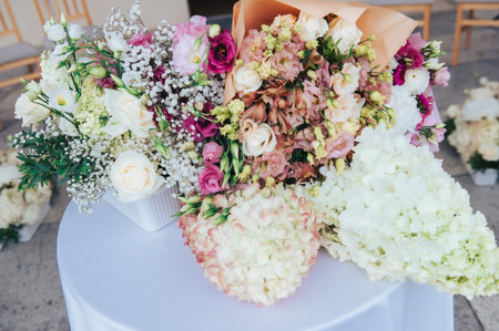 Multiple wedding flower arrangements placed on round table during formal ceremony in Latvia.の写真素材
