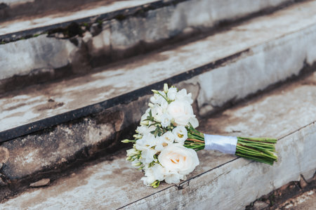 Close view of white wedding bouquet resting on old stone steps during outdoor ceremony in Latvia.の写真素材