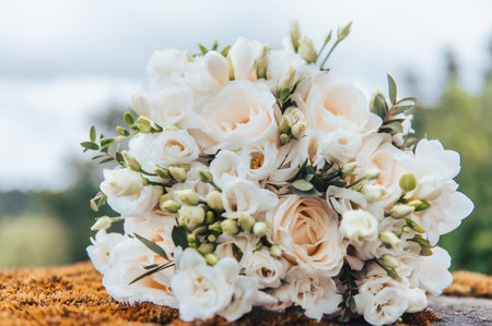 Close view of white wedding bouquet resting on moss stone with soft natural light in Latvia.の写真素材