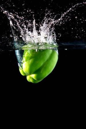 Fresh green paprika splash in water on black backgroundの写真素材