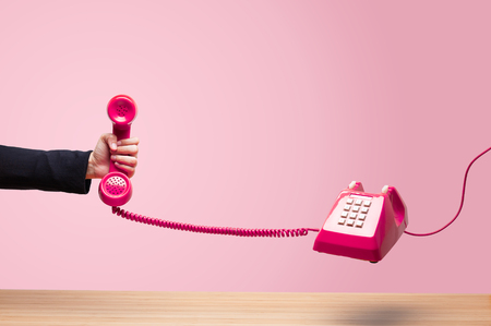 Business woman holding the red phone, urgent call waiting , classic red telephone receiver in hand...