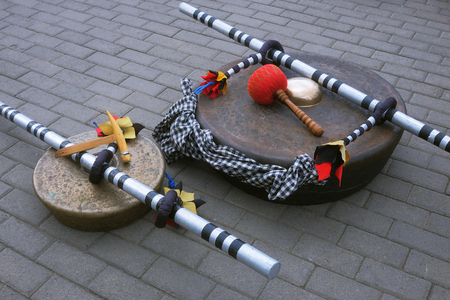 Traditional indonesian balinese musical instruments gongs lying down on the tiled floor between ceremonial compositions.の写真素材