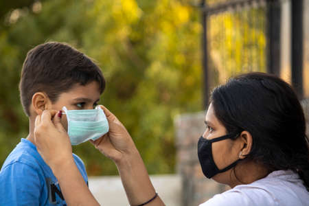 Mother help child to wear mask in india to protect him against flu and virusの写真素材
