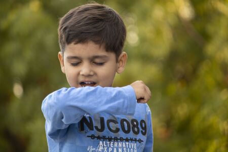 Indian child coughing on his elbow showing tips to protecting corona virusの写真素材