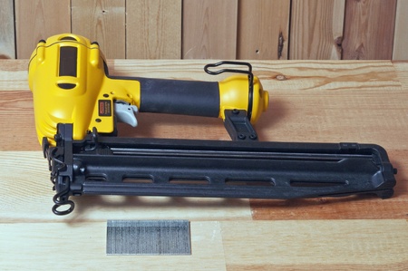 yellow nail gun and nails on wood backgroundの写真素材