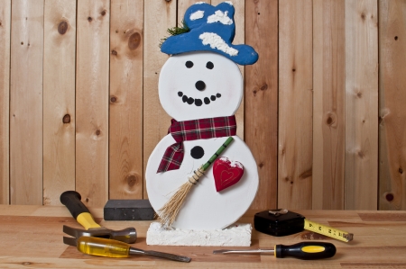 Holiday craft wooden snowman and tools on wood backgroundの写真素材