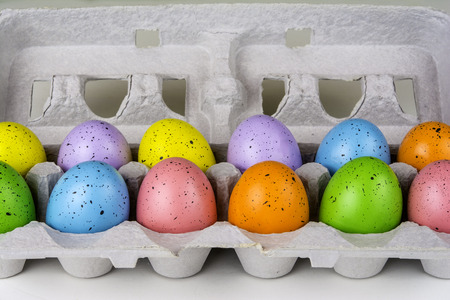 colored Easter eggs in grey cardboard crateの写真素材