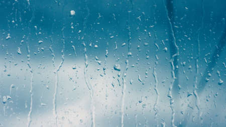 Rain drops close up on window glass outdoors. Texture of water in heavy rain. Gloomy autumn morning. Macroの写真素材