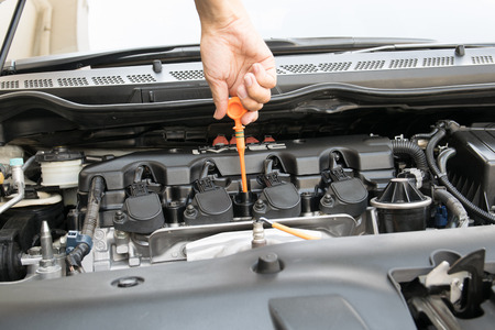 Man checking oil in his car using dipstickの写真素材