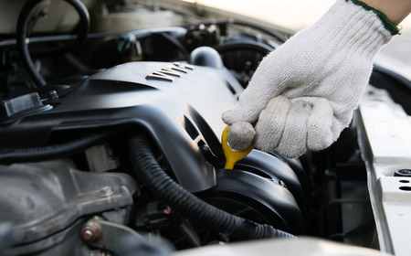 Man checking oil in his car using dipstick