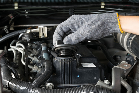 A mechanic is opening the oil cap from a car engine.の写真素材