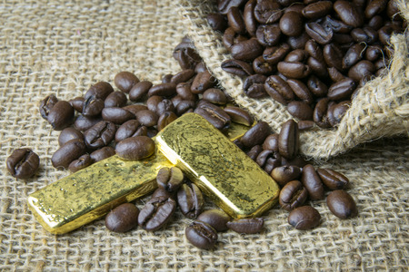 Coffee beans and Gold Bullion in sackcloth bag on wooden backgroundの写真素材