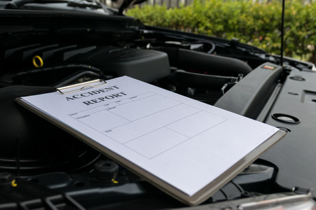 Mechanic Inspecting damage car and filling in accident report form