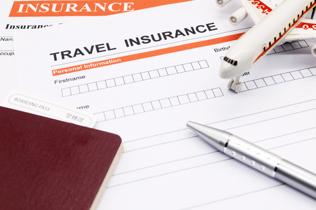 Travel insurance application form with plane model and pen and passportの写真素材