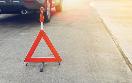 Broken car sign on a road with a broken down car