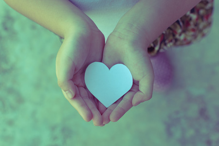 Children hands holding small model of heart and family , concept familyの写真素材