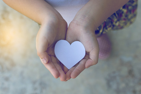 Children hands holding small model of heart and family , concept familyの写真素材
