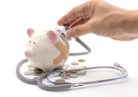 Doctor Holding Stethoscope to Piggy Bankの写真素材