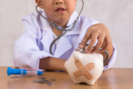 Asian boy playing as a doctor care Piggy Bankの写真素材