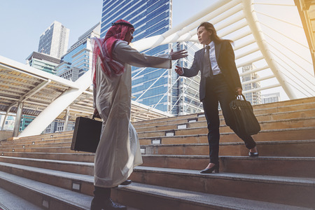 Arab businessman and businesswoman handshaking in city の写真素材