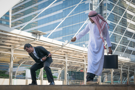 Arab businessmen and businessman playing tug of war on city backgroundの写真素材