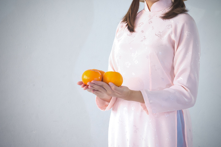 beautiful woman in pink dress and vietnam hat holding orangeの写真素材