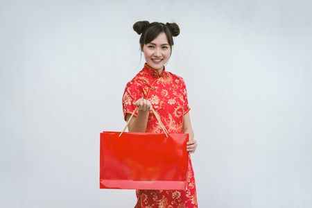 Asian woman holding shopping bag, woman wear cheongsam, chinese new yearの写真素材