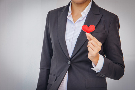 Asian businesswoman wearing a black suit holding a red heartの写真素材