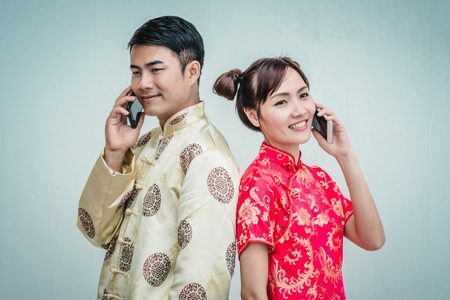 Young chinese couple with cheongsam holding smartphone.の写真素材