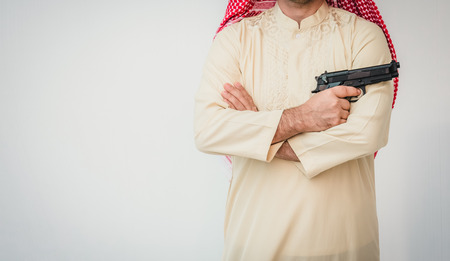 Arab man standing with hand holding gunの写真素材