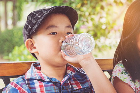 Boy drinks water from a bottleの写真素材