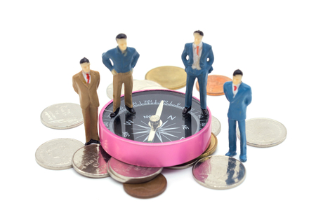 Miniature businessman and compass on coins stack on white backgroundの写真素材