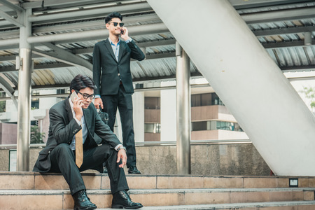 Business team working at city, looking a mobile phoneの写真素材