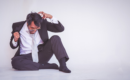 Depressed businessman sitting on the floorの写真素材