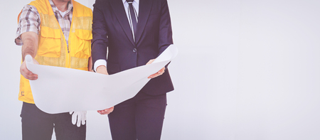 Construction manager and engineer looking at blueprintsの写真素材