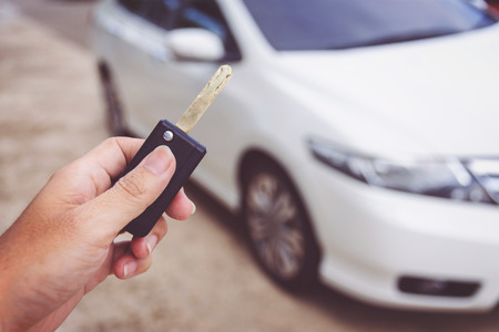Man holding car keys with car on backgroundの写真素材