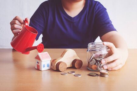 Boy watering car and house and coins. plan for House conceptの写真素材
