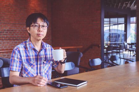 Young asian man drinking coffee in cafe の写真素材