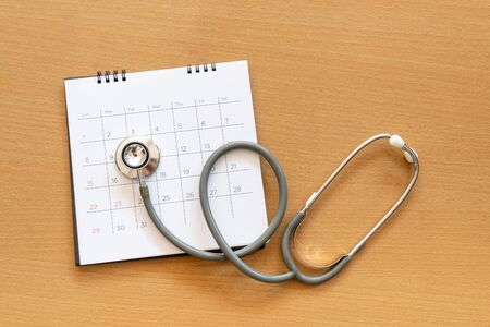 stethoscope and calendar on wooden table, schedule to check up healthy conceptの写真素材