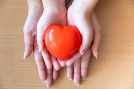 mother and daughter hands holding red heart, health care, donate and family insurance concept