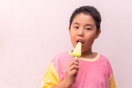 Asian boy eating a colorful frozen  in the summerの写真素材