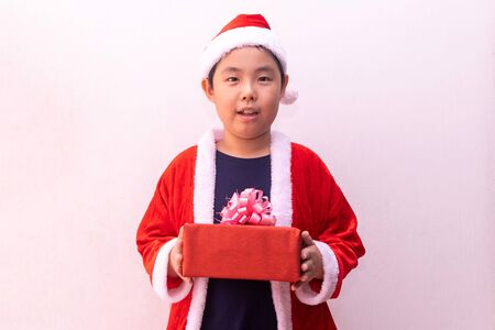 Asian boy in Santa Claus clothes holding gift. Merry christmasの写真素材