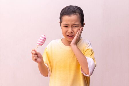 Asian girl  hypersensitive teeth eating eating a colorful frozen  in the summerの写真素材