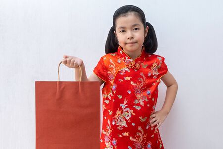 Asian girl wear cheongsam hold shopping paper bag. chinese new year. holiday and celebrate concept.の写真素材