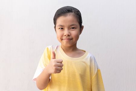 Asian girl making thumb up sign and smiling cheerfully,の写真素材